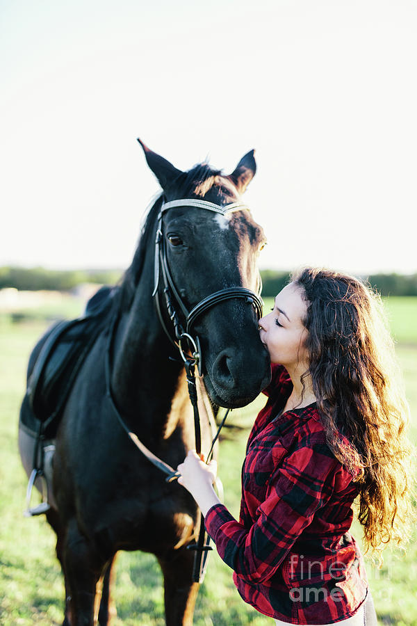 Black horse kissed by a young woman. Photograph by Michal Bednarek