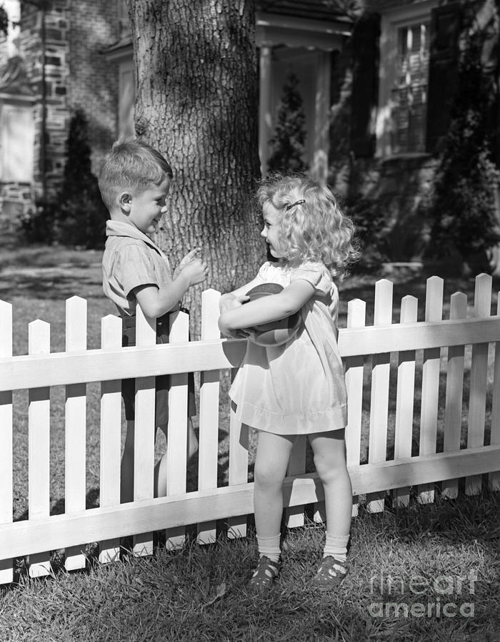 Boy And Girl Talking Over Fence, C.1940s Photograph by H. Armstrong Roberts/ClassicStock