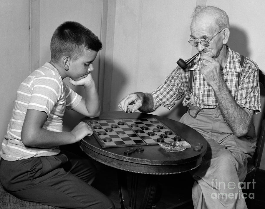 Boy Playing Checkers With Grandfather Photograph by Debrocke/ClassicStock