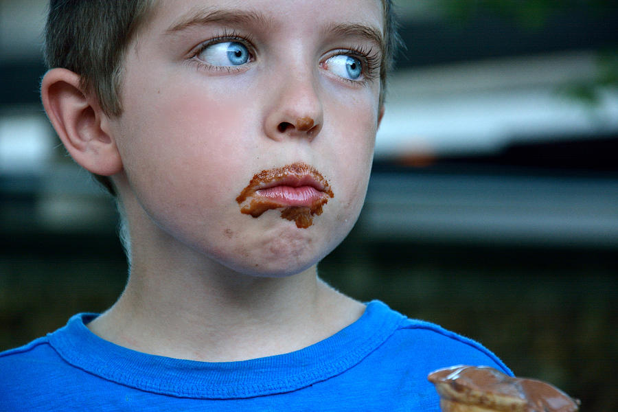 Boy with dirty chocolate face eating ice cream Photograph by Serena King