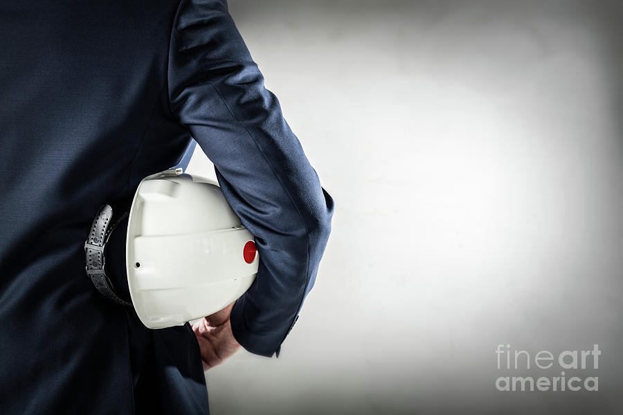 Businessman holding white safety helmet. Photograph by Michal Bednarek