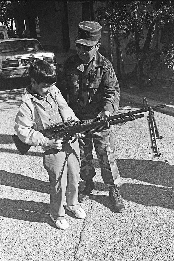 Camouflaged dressed soldier teaching boy how to shoot machine gun Tucson Arizona Photograph by David Lee Guss