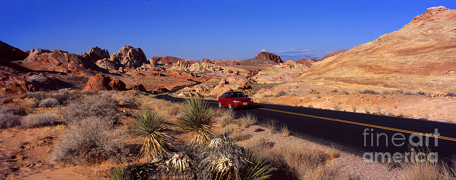 Car in the Valley of Fire Roadway in Flaming Rock Shapes Photograph by Wernher Krutein