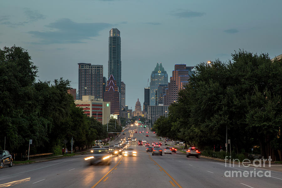 Rush Hour Movie Photograph - Cars drive past the Congress Avenue Bridge the gateway to the hip and eclectic South Congress Avenue with Texas Capitol and Skyline backdrop by Dan Herron