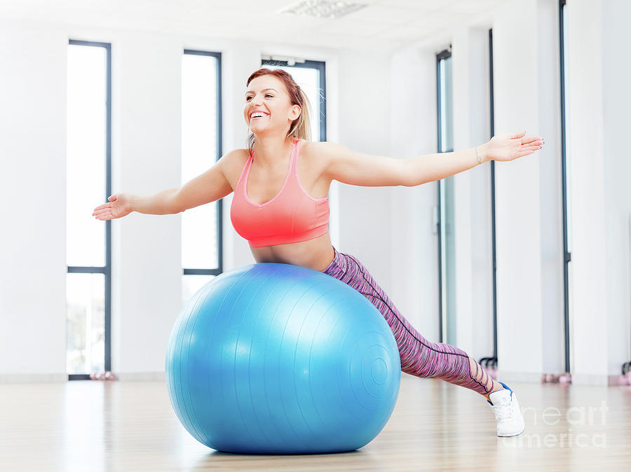 Cheerful woman training with fitball at fitness club. Photograph by Michal Bednarek