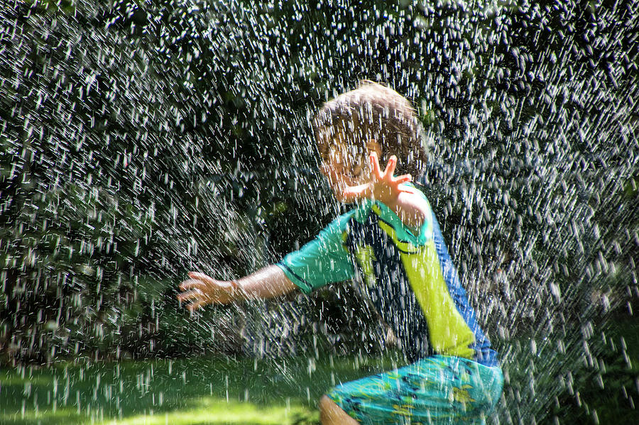 Child running through the Water Sprinkler Photograph by Randall Nyhof