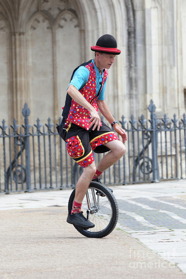 Clown riding unicycle in town Photograph by Simon Bratt