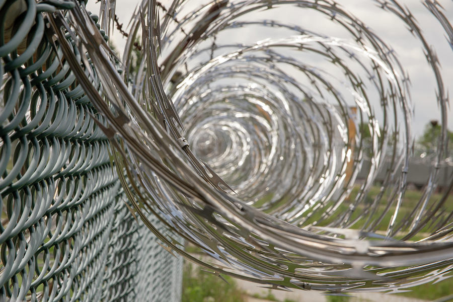 Abandoned Photograph - Coiled razor wire on fence by Karen Foley