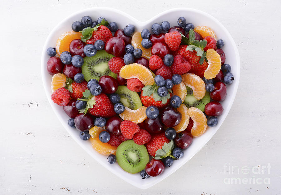 Colorful rainbow fruit in heart shape bowl. Photograph by Milleflore Images