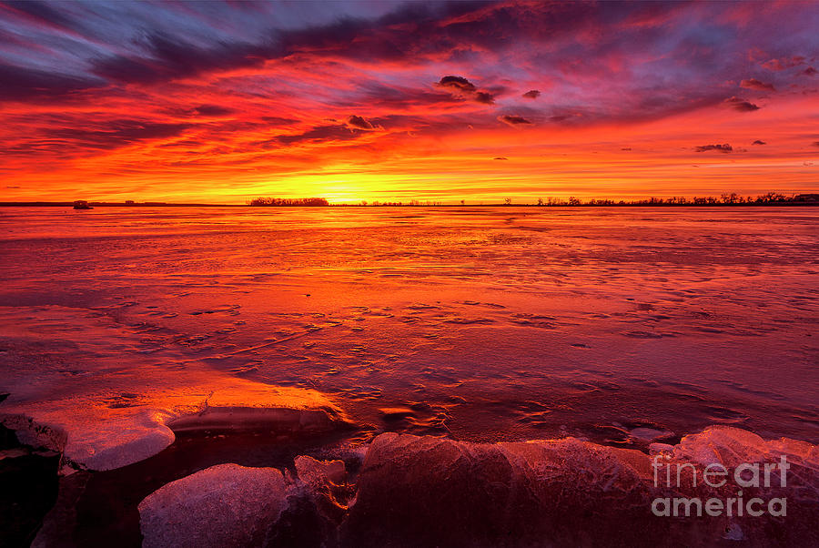 Colorful Sunrise or Sunset on a frozen lake with rocks in the fo Photograph by Ronda Kimbrow