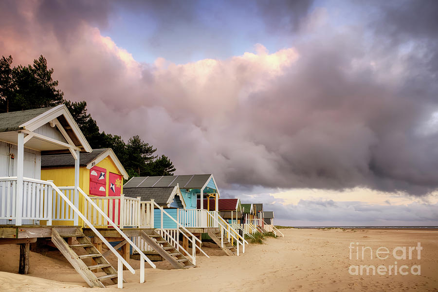 Colourful beach huts on golden sand coast Photograph by Simon Bratt