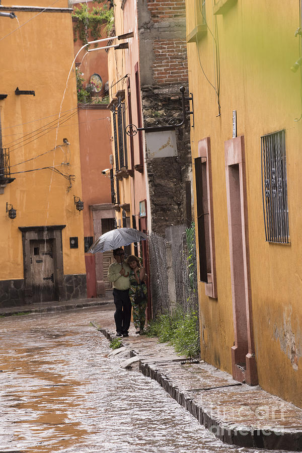 Couple walking in the rain through old San Miguel Mexico Photograph by Juli Scalzi
