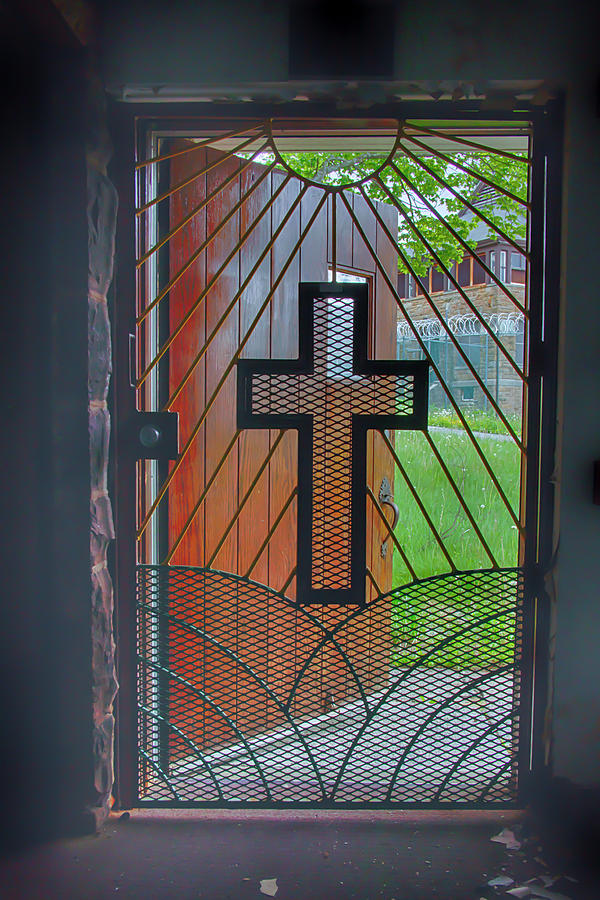 Cross on church door open to prison yard with light Photograph by Karen Foley