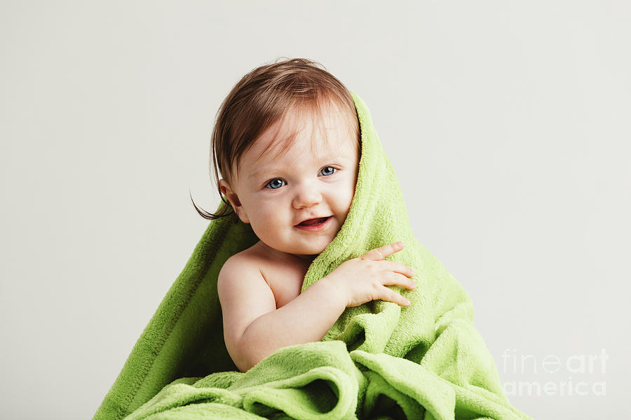 Cute little baby leaning out of cozy green blanket. Photograph by Michal Bednarek