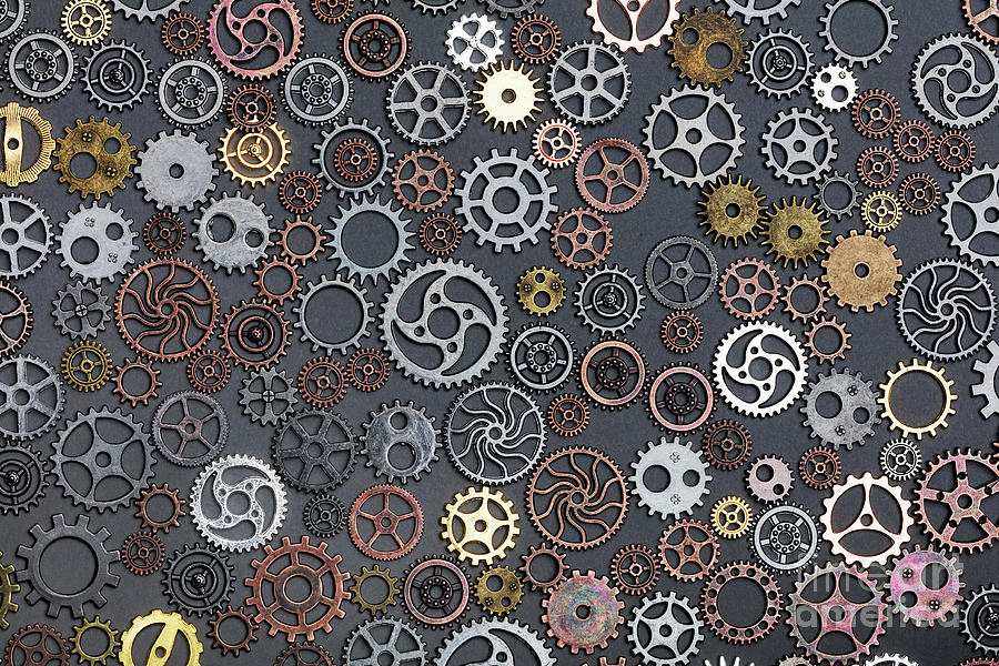Different cogwheels laying on grey background. Photograph by Michal Bednarek