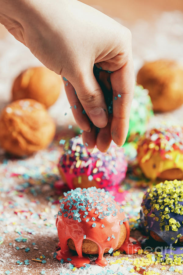 Doughnuts sprinkled by a woman with sugar sprinkles. Photograph by Michal Bednarek