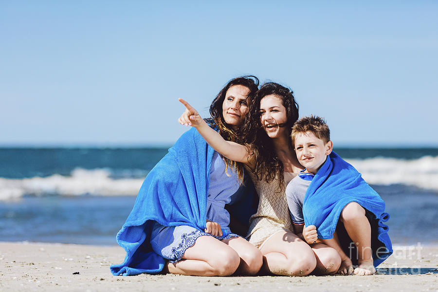 Family sitting on a beach, older sister pointing her finger Photograph by Michal Bednarek