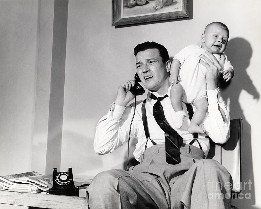 Father Holding Baby While On The Phone Photograph by Debrocke/ClassicStock