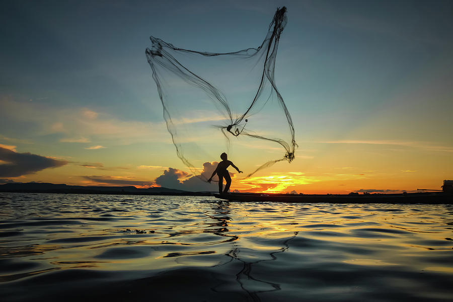 Fisherman throwing net by Visoot Uthairam
