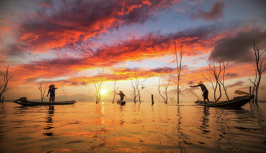 Fisherman working with net on the boat and sunset background Photograph by Anek Suwannaphoom