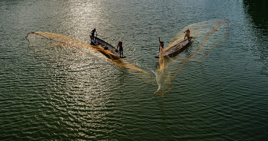 Fishermen throw fishing net on boats to catch fish Photograph by