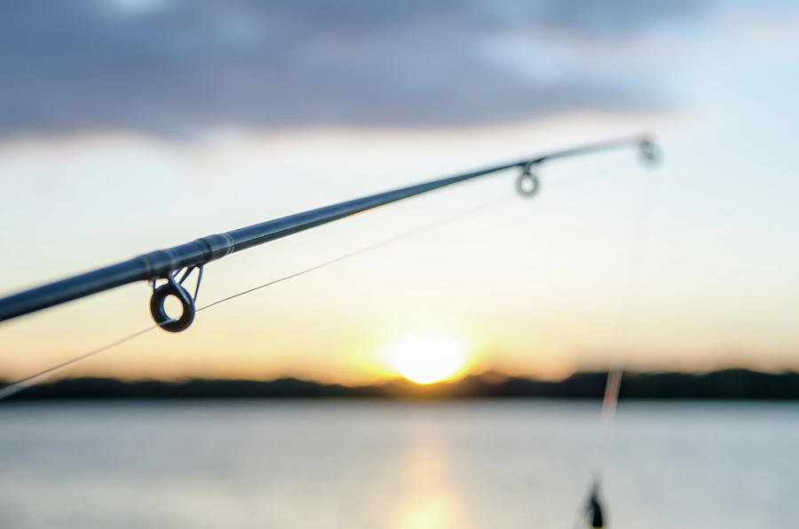 Fishing Rod With Lure At Sunset Over A Lake Photograph by Alex