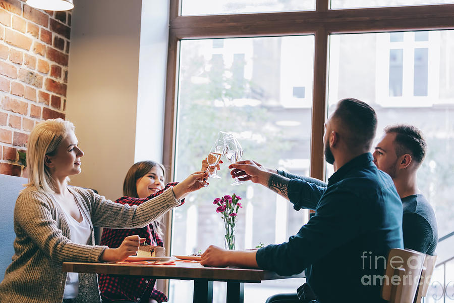 Four friends sitting together with glasses of champagne. Photograph by Michal Bednarek