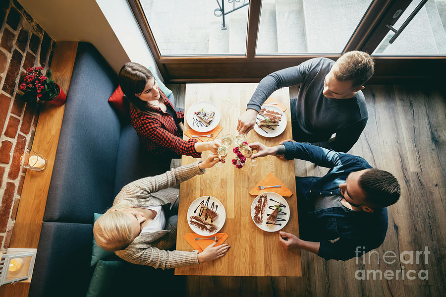 Cake Photograph - Four friends toasting in a restaurant. Top view. by Michal Bednarek