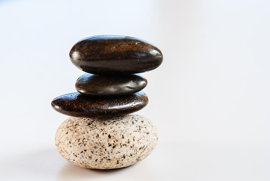 Pebbles Photograph - Four pebbles balanced on white background by Vishwanath Bhat