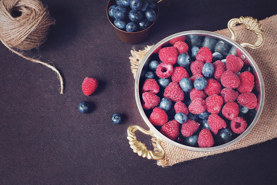 Blueberry Photograph - Fresh raspberries and blueberries dark picture with copy space on left. Fresh fruits, berries in an old copper cup, bowl. Dark Styled Stock Photo, Black Background by Sevda Stancheva