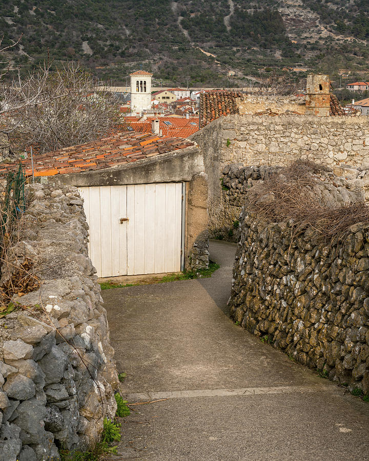 Garage with wooden white door, narrow street in Cres Photograph by ...