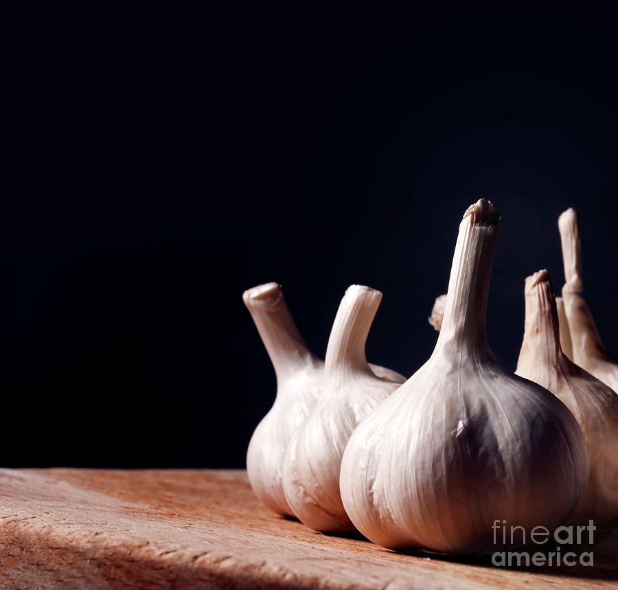 Garlic bulbs on wooden table Photograph by Jelena Jovanovic