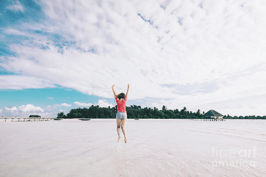 Girl jumping on a sandy beach. Fun time on Maldives Photograph by Michal Bednarek