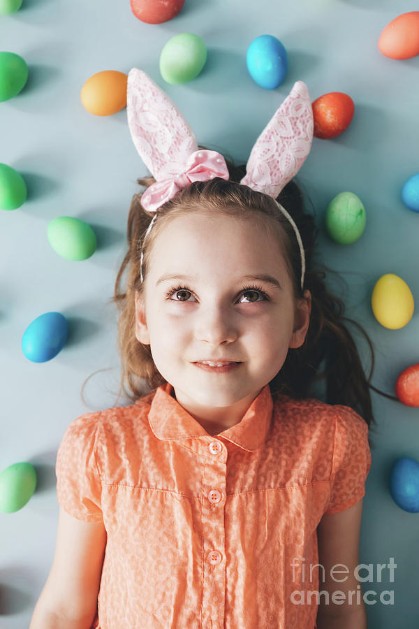 Girl with bunny ears surrounded by colorful eggs. Photograph by Michal Bednarek