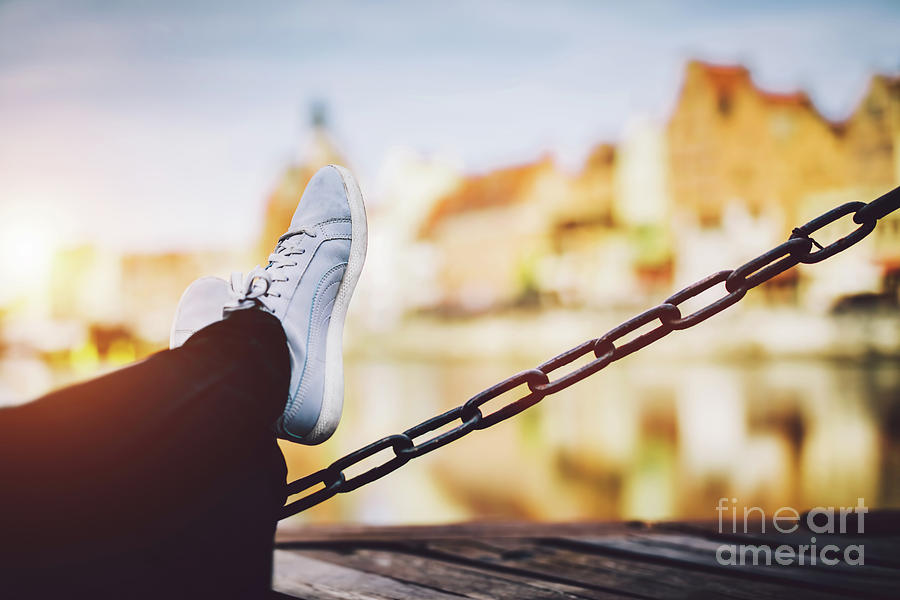 Girls legs leaning on a chain, a river and old buildings in background Photograph by Michal Bednarek