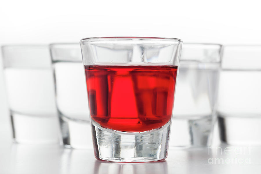Glasses of alcohol. One red flavoured, the others clean vodka Photograph by Michal Bednarek