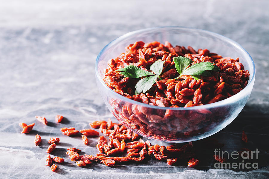 Fruit Photograph - Goji berries and green leaves in a glass bowl by Michal Bednarek