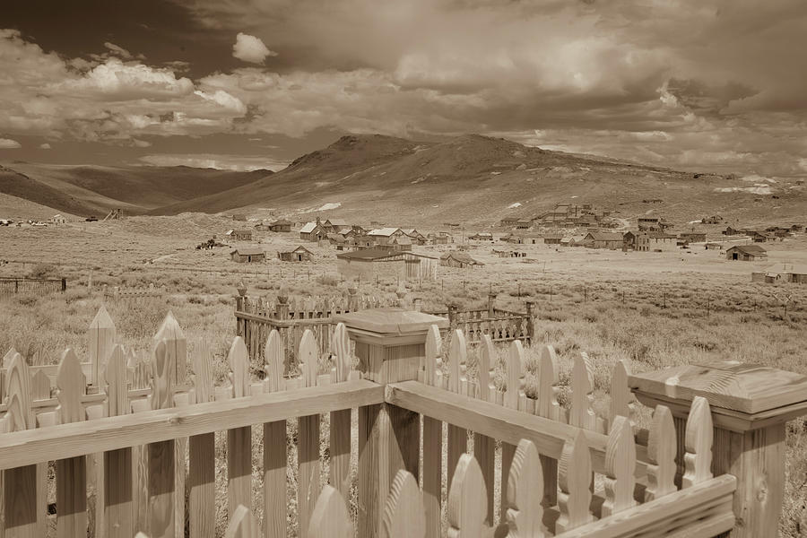Graves in cemetery over Bodie, California in sepia Photograph by Karen Foley