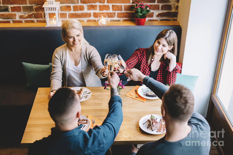 Toast Photograph - Group of friends toasting in a restaurant. by Michal Bednarek