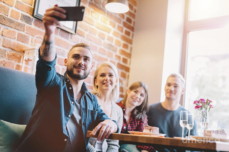 Man Photograph - Group of people taking a selfie together in a restaurant. by Michal Bednarek