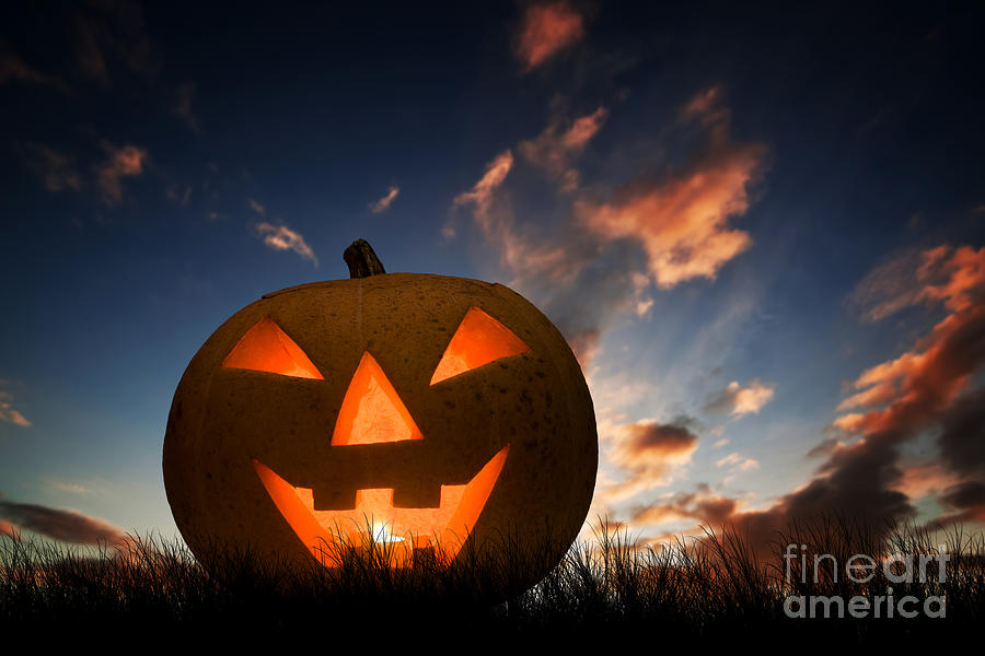 Halloween pumpkin glowing under dark sunset, night sky. Jack o'lantern