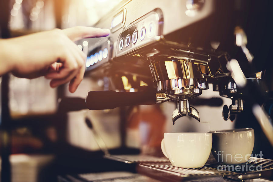 Hand pressing the button on a coffee machine. Coffee preparation. Photograph by Michal Bednarek