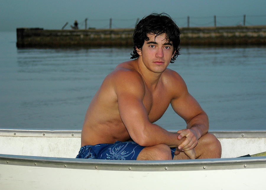 Handsome athletic male sitting half-naked in a rowboat.  Photograph by Gunther Allen