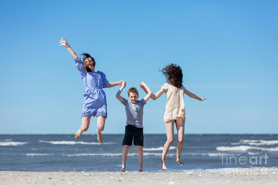 Happy family jumping high on the seashore. Photograph by Michal Bednarek