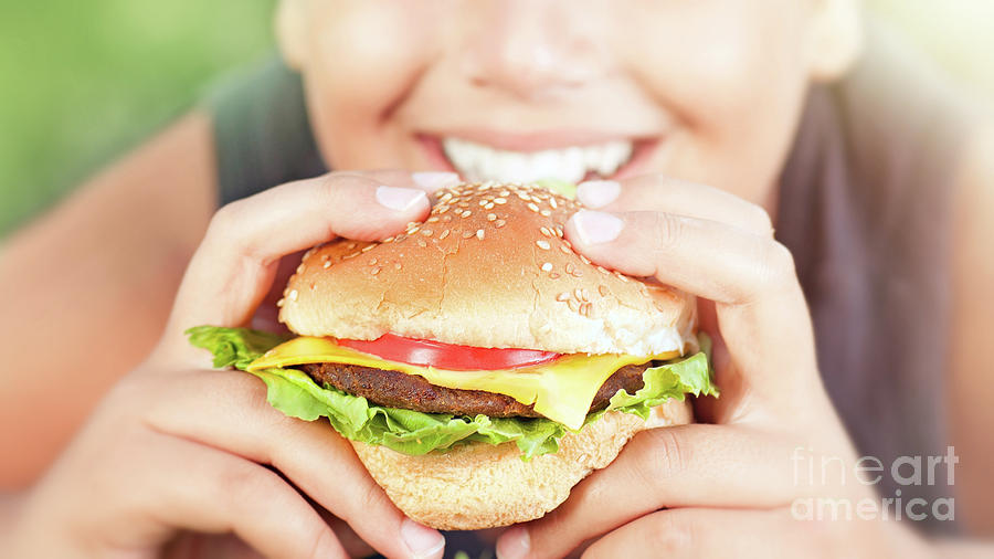 Happy teen boy eating burger Photograph by Anna Om