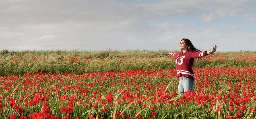 Happy Teenage Girl standing  in a red field of poppy flowers  Photograph by Michalakis Ppalis