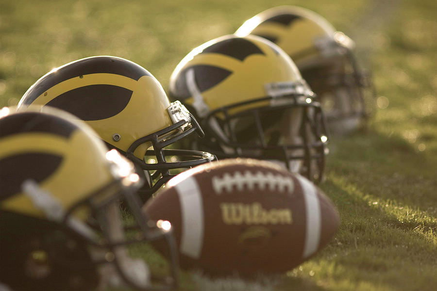 Helmets and a Football on the Field at Dawn by Michigan Helmet Helmets and a Football on the Field at Dawn by Michigan Helmet