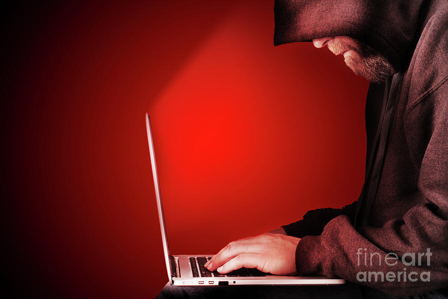 Hooded computer hacker red background Photograph by Simon Bratt