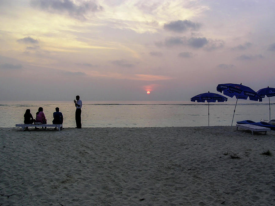 Host gesturing to a tourist family at sunrise in the Lakshadweep Photograph by Ashish Agarwal