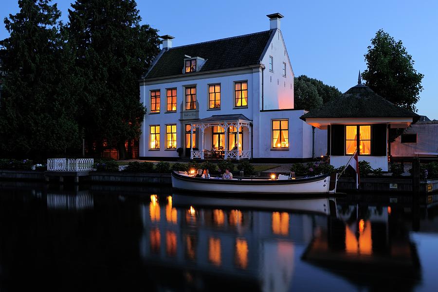 Illuminated house at the river Vecht in the Netherlands in the evening Photograph by Merijn Van der Vliet